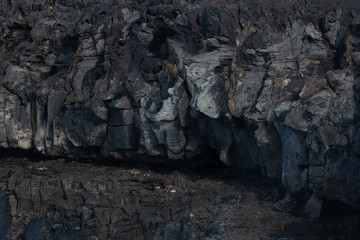 Part of the relief wall of the mountain of frozen lava in black tones, shot from close range