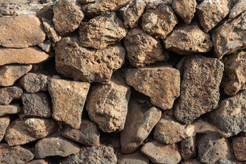 Wall of carefully selected raw natural stones with deep gaps close-up in daylight
