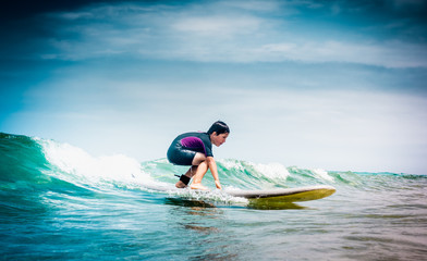 Teen boy surfing on sea waves
