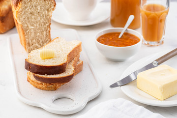 Freshly brioche bread and butter, juice and jam. Continental breakfast.