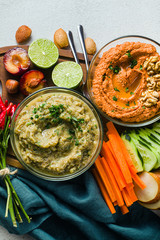 veggie serving table with snacks with vegetables, fruits, baba ganoush and dip or spread of roasted red pepper and nuts. healthy vegan food for celebration or friends. shot from above. copy space