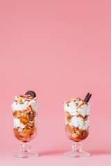 Sweet dessert in glass with biscuit and whipped cream on pink bsckground, selective focus and blank space