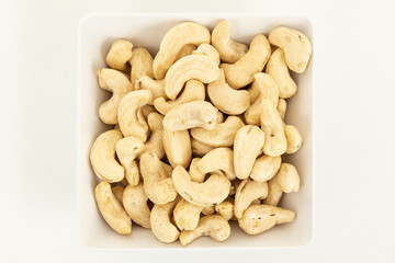 Cashew nut nut dried fruit in bowl on white background. Top view