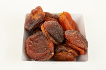 Bowl of dried apricots, on white background.