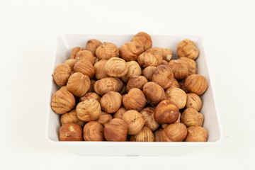 peeled hazelnuts in a white bowl on a white background