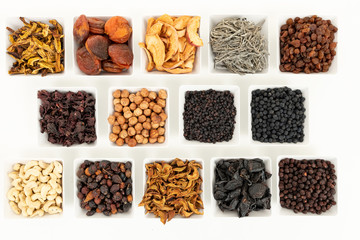 Groups of various kinds of dried fruits in square white bowls on white background