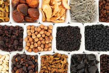 Groups of various kinds of dried fruits in square white bowls on white background