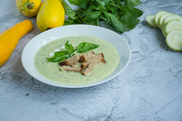 Cream soup of mashed potatoes with zucchini and basil and crackers . Space for text.