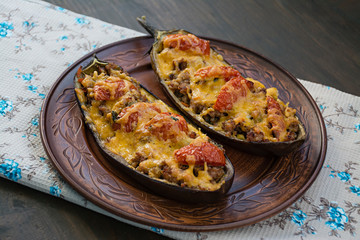 Stuffed Eggplant. Eggplant with minced meat, vegetables and herbs. Wood background.