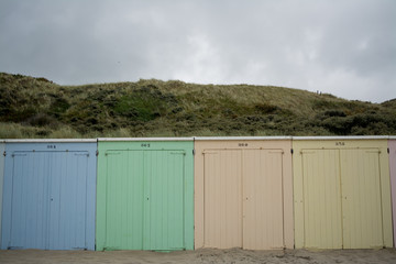 Wooden beach huts in front of a Dune