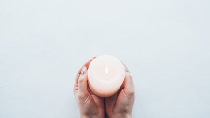 Peace and harmony. Top view of candle in lady tender hands over white background. Copy space.