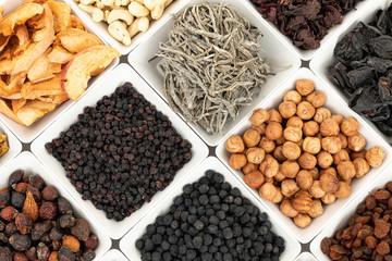 Groups of various kinds of dried fruits in square white bowls on white background