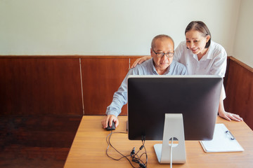 Senior Couple Looking At Desktop Computer At Desk