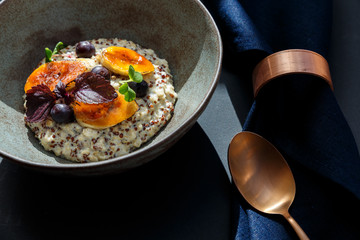 oatmeal in a bowl with bananas and blueberries on a table with blue napkin and bronze spoon