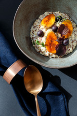 oatmeal in a bowl with bananas and blueberries on a table with blue napkin and bronze spoon