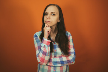 A beautiful woman in a plaid shirt poses on an orange background.