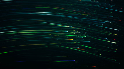 Blur multicolor flowing lights. Defocused neon green and blue illuminated lines and sparkles. Dark abstract background.