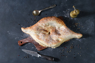 Georgian bread lavash on wooden board on dark rustic background, top view