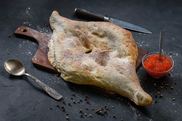 Georgian bread lavash with red caviar on wooden board on dark rustic background, top view