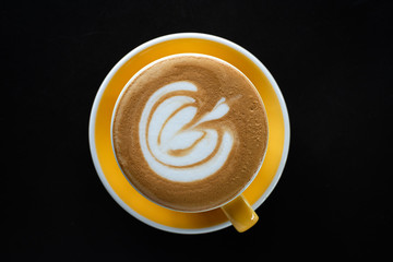 A cup of coffee with beautiful latte art on black table background.