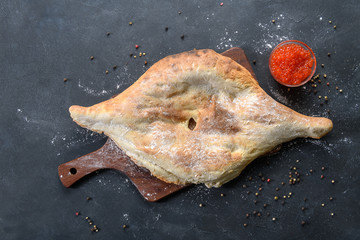Georgian bread lavash with red caviar on wooden board on dark rustic background, top view