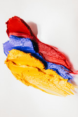 Makeup art. Decorative cosmetics. Yellow blue red lipstick samples on white background.