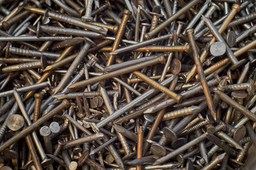 A bunch of different iron construction nails, close-up. Abstract background.