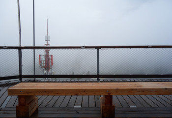 Wooden bench on top of observation tower on nature in fog