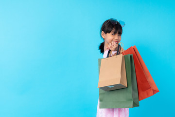 happy young Asian girl kid stylish holding shopping bag on blue background in studio, lifestyle of paid for kids fashion style concept