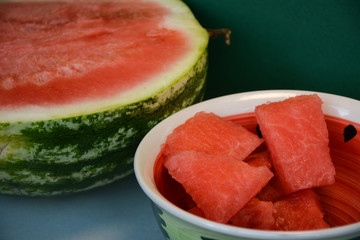Sliced ​​ripe red watermelon and sliced ​​pieces in a stylish plate on a green background