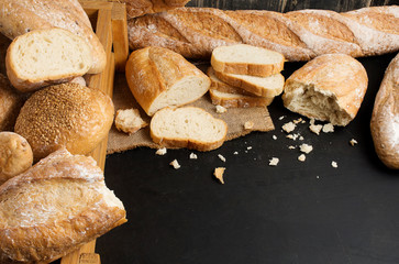 Bread and sliced ​​bread on the black stone table The top view has space to compose your message.