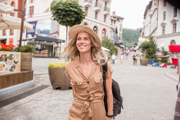 Fototapeta premium Happy young caucasian woman stylish traveler with hat walks around european city. Charming young female student enjoying European country vacation. Travel new impressions concept