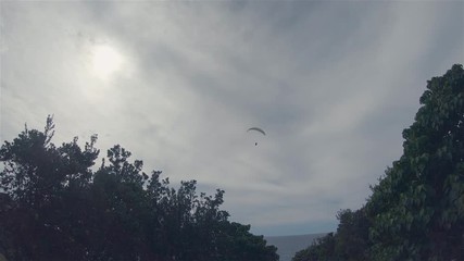 Paraglider Paragliding. Para Glider Para Gliding & Flying High In Windy Cloudy Sky At Lennox Point Over Sea Coastline Trees. Popular Outdoor Leisure Activity.Lennox Head Landscape Australia