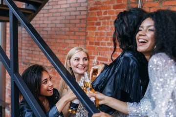 Multi-ethnic friends standing on the staircase with bottles of beer