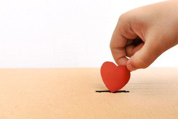 Kid hand insert heart in donation box