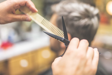 Barber cutting and modeling hair with scissors and comb.