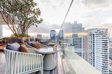 Outdoor rooftop bar with outdoor sofa sets in the evening. This space can take a view of modern...