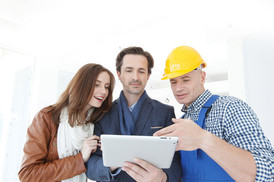 Worker and couple look at tablet