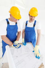 Builders in hardhats with blueprint