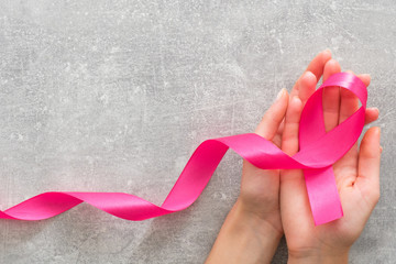 Woman’s hands holding pink breast cancer awareness ribbon. Healthcare and medicine concept