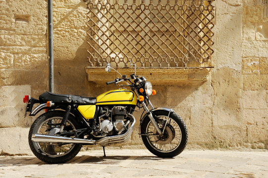 Vintage yellow motorcycle standing in the street  of old italian town. Lecce, Apulia, Italy