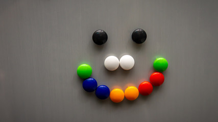 Smiley emoji using the colorful fridge magnet on the refrigerator.