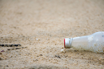 Glass bottle throw on the sand by human in the beach it's cause of garbage in ocean and environmental pollution.