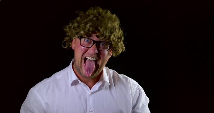Portrait of a mad man with curly hair and glasses. Show tongue and fool around on black background