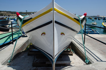 Front view on a traditional white maltese fisherman boat with protective eyes
