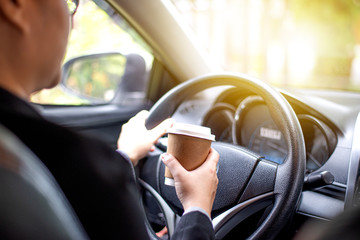 Naklejka premium Business woman's hand holding a coffee cup to take away, she is driving in the morning