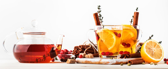 Winter or autumn healing hot tea with lemon, cranberries, thyme and spices, white background, copy space, selective focus