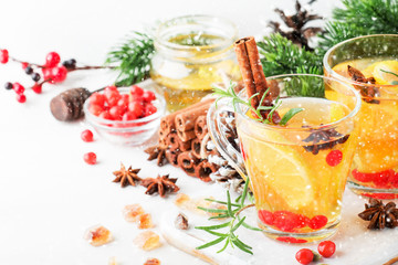 Winter hot tea with lemon, cranberries, herbs and spices for Christmas or New Year evening, white background, copy space, selective focus