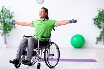 Young man in wheel-chair doing exercises indoors