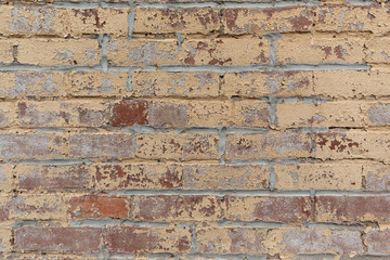 Old red brick wall with peeling yellow paint texture